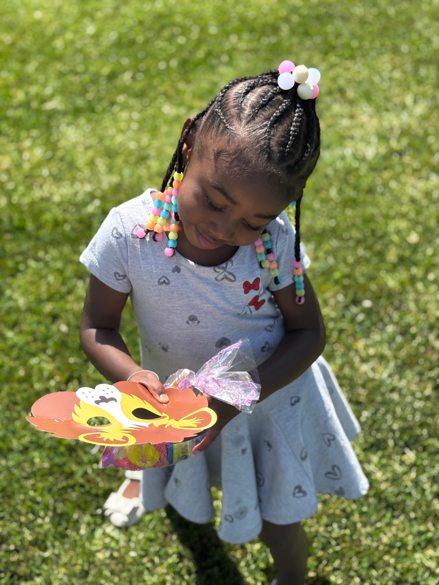 A child playing outside in the grass with a lion mask