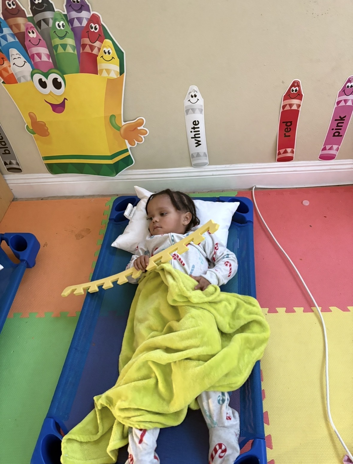 Toddler resting on a colorful cot at nap time