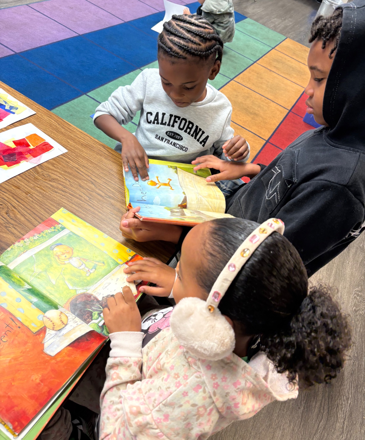 Preschoolers reading picture books together at the classroom table