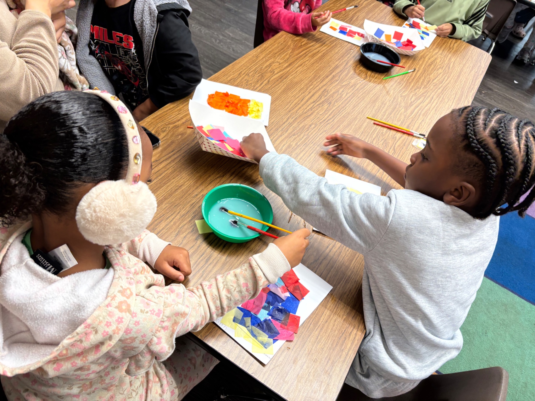 Children collaborating on a colorful tissue paper art project
